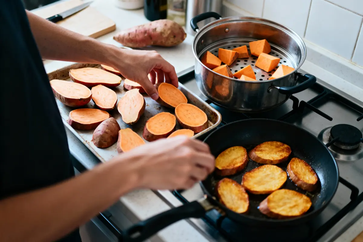 Personne cuisinant des patates douces sur une cuisinière, avec tranches au four et dans poêle.
