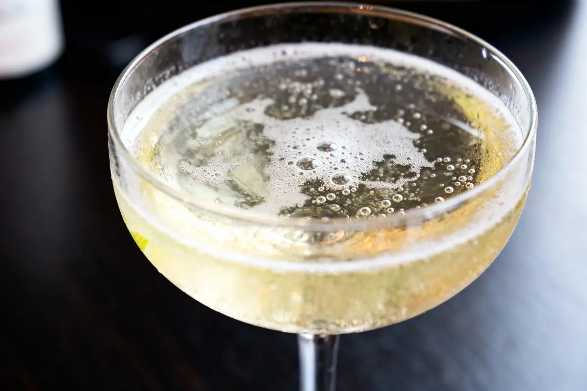 Verre de champagne pétillant sur table noire, bulles visibles en gros plan.