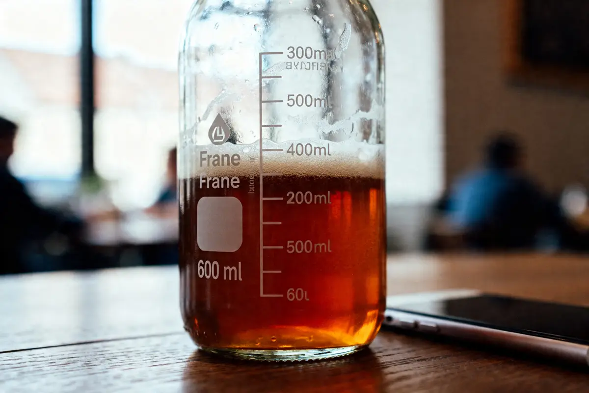 Verre gradué contenant du liquide ambré mesurant 60 cl en ml sur une table en bois