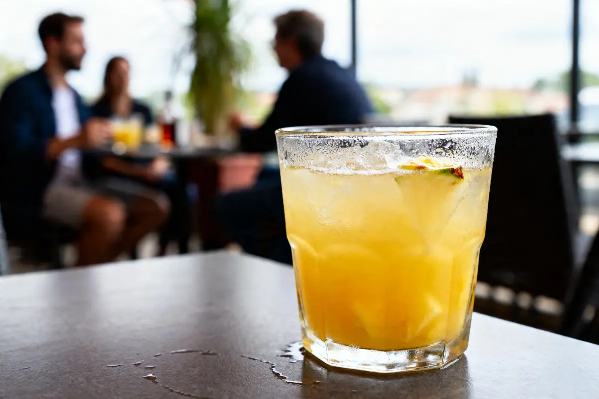 Verre de cocktail Madeleine sur une table avec des personnes floues en arrière-plan