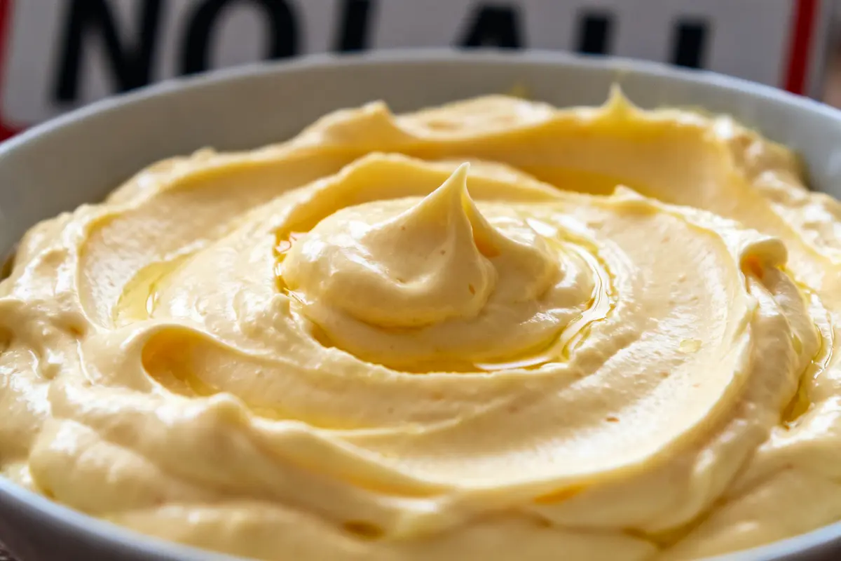 Bol de mayonnaise sans moutarde crémeuse aux reflets jaunes en gros plan